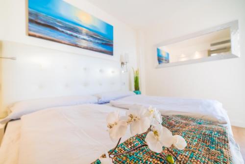 a white bed with white flowers on top of it at Sa Maniga 5E in Cala Millor