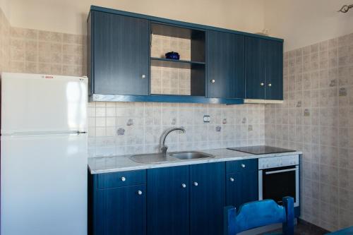 a kitchen with blue cabinets and a sink and a refrigerator at Aristeides - Moscha Apartments in Platis Yialos Sifnos