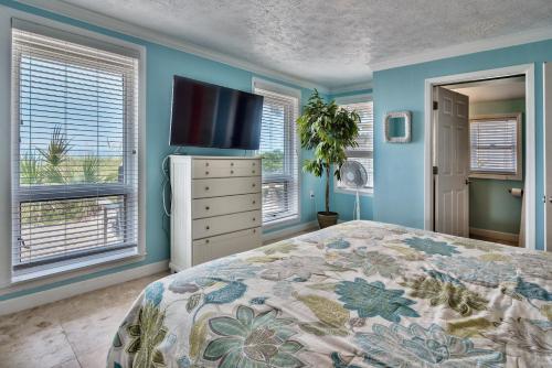 Schlafzimmer mit blauen Wänden und einem Bett mit einem TV in der Unterkunft Sand Blast - Lovely Beachfront Home With Tons Of Space! in Panama City Beach