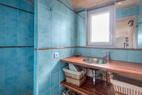 a blue tiled bathroom with a sink and a window at Maison Campanule in La Flotte