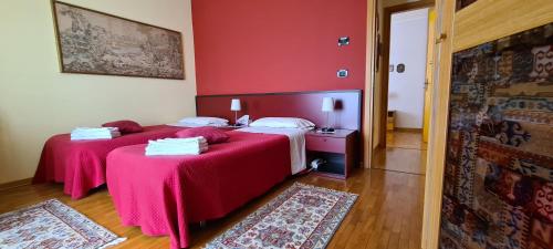 two beds in a room with red walls at B&B Isonzo in Turriaco