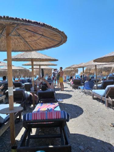 a beach with chairs and umbrellas and people on the beach at Panorama in Pefki