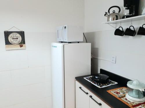 Una cocina con un refrigerador blanco y una encimera. en Amplo, aconchegante e pertinho de tudo, en Porto Alegre