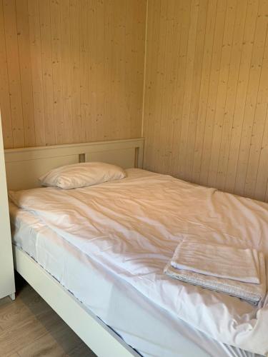 1 cama con sábanas blancas y almohadas en una habitación en Mjøsvang Kafe, en Vang I Valdres