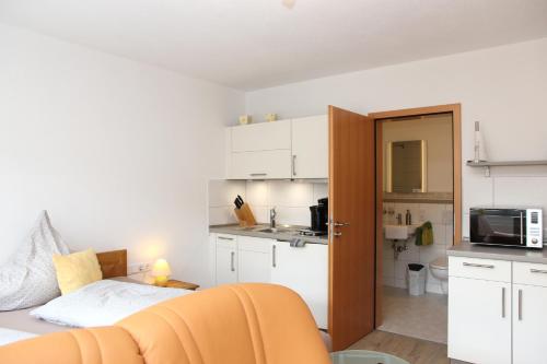 a room with a bed and a kitchen with white cabinets at Pension und Ferienwohnungen Schweinsberg in Medebach