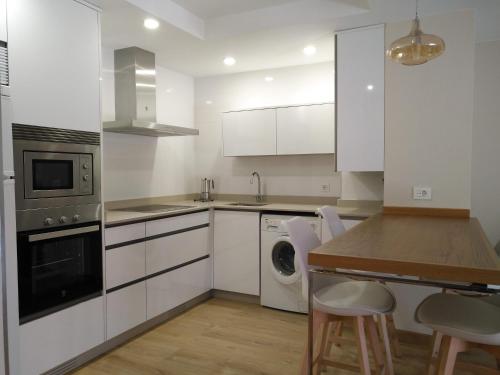cocina con armarios blancos y mesa de madera en Apartamento El Manin, en Villaviciosa