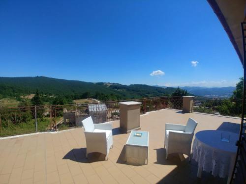 a patio with white chairs and a table with a view at Terrazza sul cielo in Bella