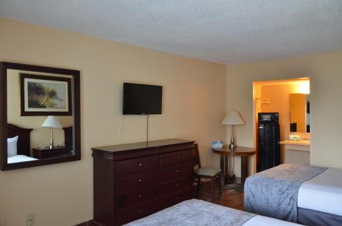 a bedroom with a bed and a dresser with a television at Altamonte Springs Hotel and Suites in Orlando