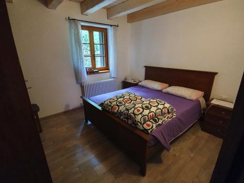 a bedroom with a bed with purple sheets and a window at Buine Tiere in Cercivento