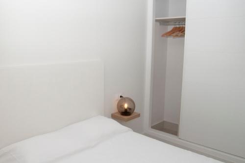 biała sypialnia z łóżkiem i małą lampką w obiekcie El mirador de Ancha w Kadyksie