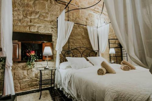 Durmiendo como Reyes en la Rioja في Cihuri: غرفة نوم بسرير وجدار حجري