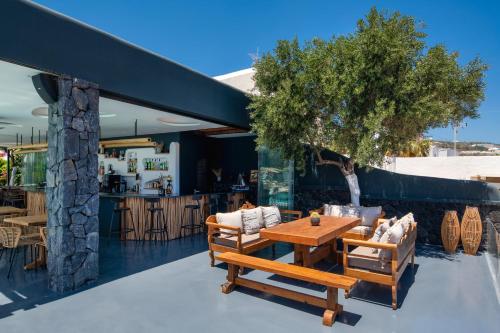 a patio with a table and chairs and a tree at San Marino Suites by Calm Collection in Fira