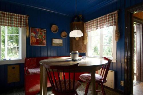 a dining room with blue walls and a table and chairs at Ett hus för romantisk semester in Lammhult