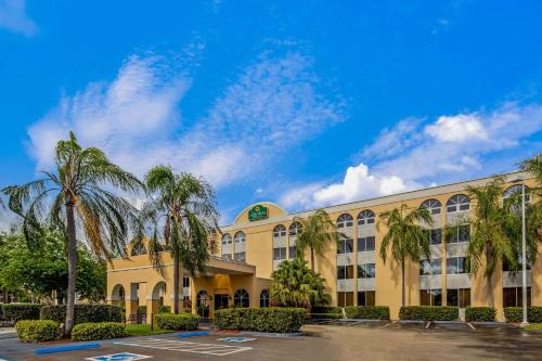 a large building with palm trees in a parking lot at La Quinta by Wyndham Miami Lakes in Miami Lakes