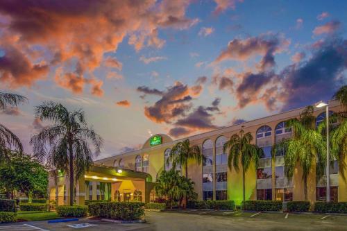 un edificio con palmeras frente a la puesta de sol en La Quinta by Wyndham Miami Lakes en Miami Lakes
