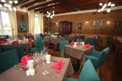 une salle à manger avec des tables, des chaises et des serviettes rouges dans l'établissement RELAIS DU TAURION, à Saint-Priest-Taurion