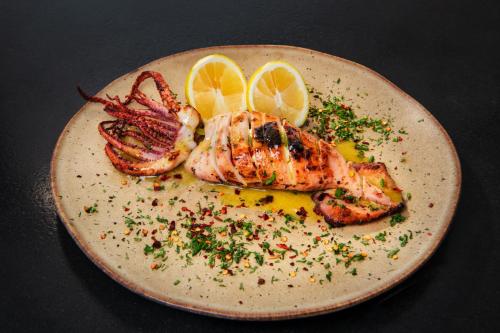a plate of food with lobster and lemon slices at San Marino Suites by Calm Collection in Fira