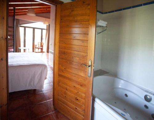 een badkamer met een bad en een slaapkamer met een bed bij L'Hotelet d'Estamariu in Estamariu