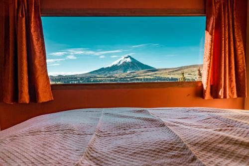 a view of a mountain from a bedroom window at The Secret Garden Cotopaxi in Hacienda Porvenir