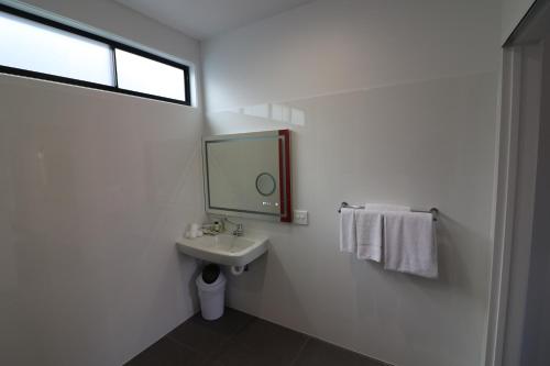 a bathroom with a sink, toilet and mirror at Room Motels Kingaroy in Kingaroy
