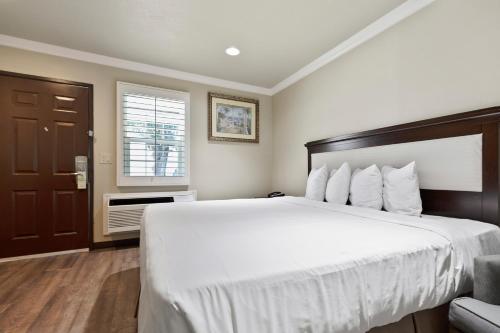 a bedroom with a large white bed and a window at Le Blanc Inn & Suites in El Monte