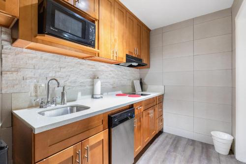 a small kitchen with a sink and a microwave at Le Blanc Inn & Suites in El Monte
