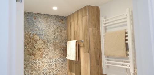 y baño con ducha y pared de madera. en APARTMENT MARINA CALADOR HARBOURVIEW AIR CONDITION POOL GARDEN TERRASSE PORTO CARI spectacular locatio en Cala D'Or