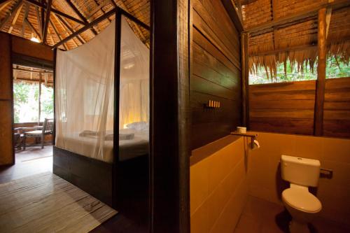 a bathroom with a toilet and a bed in a room at Rimba Resort - Dive Centre & Spa in Pulau Sibu