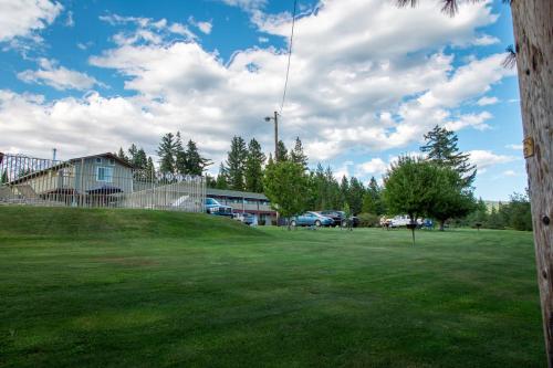 a green field with a building and cars in the background at Swiss Holiday Lodge in Mount Shasta