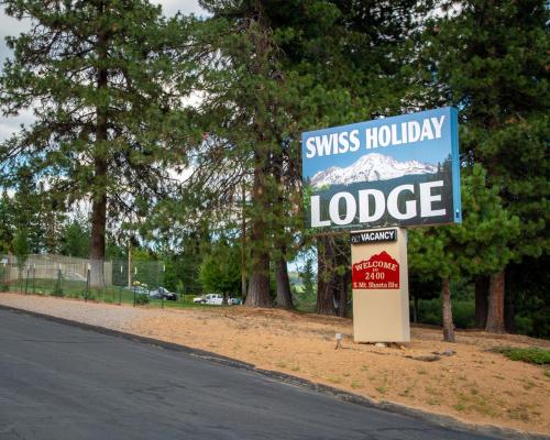 a sign for aiss holiday lodge on the side of a road at Swiss Holiday Lodge in Mount Shasta