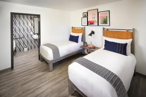 a hotel room with two beds and a mirror at voco The Tuxon by IHG in Tucson