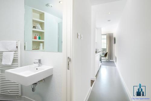 a white bathroom with a sink and a mirror at City View Apartments Rotunda in Birmingham