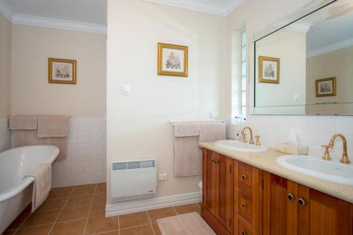a bathroom with two sinks and a tub and a mirror at Cleggett Estate Holiday Cottage in Gisborne