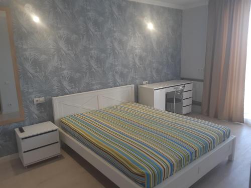 ein kleines Schlafzimmer mit einem Bett mit gestreifter Decke in der Unterkunft Apartment near stadio Metalist Kharkiv in Kharkov