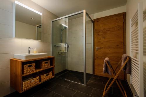 a bathroom with a sink and a glass shower at B&B Ursi in Andermatt