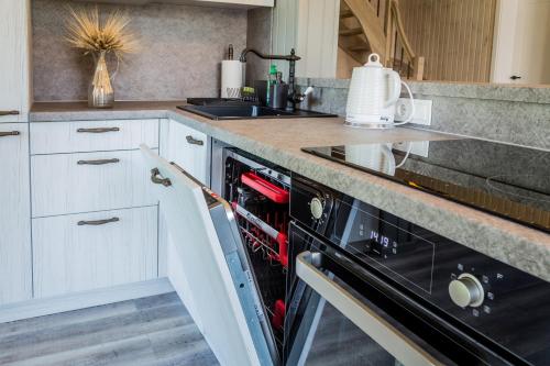 a kitchen with a black dishwasher next to a sink at Evita - 'Virš Ąžuolų' - Forest SPA - Horses - Lake in Paplatelė