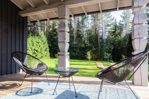 two black chairs sitting on a porch at Evita - 'Virš Ąžuolų' - Forest SPA - Horses - Lake in Paplatelė