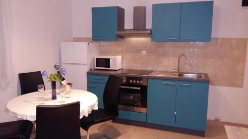 cocina con armarios azules y mesa con microondas en Apartman Dalmatino, en Sutivan
