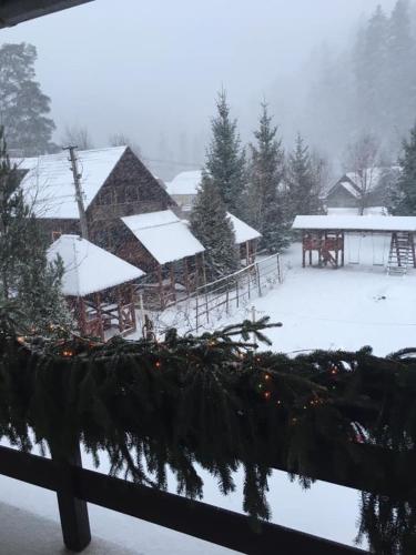 a snow covered yard with a cabin in the background at Beregynia in Zhdenievo