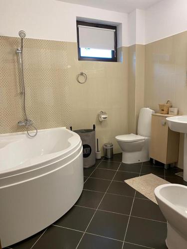 a bathroom with a tub and a toilet and a sink at La Tuya Deluxe Villa in Iaşi