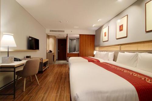 a hotel room with a large bed and a desk at Kokoon Hotel Banyuwangi in Banyuwangi
