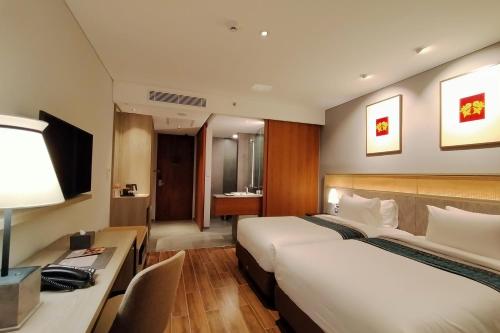 a hotel room with two beds and a desk at Kokoon Hotel Banyuwangi in Banyuwangi
