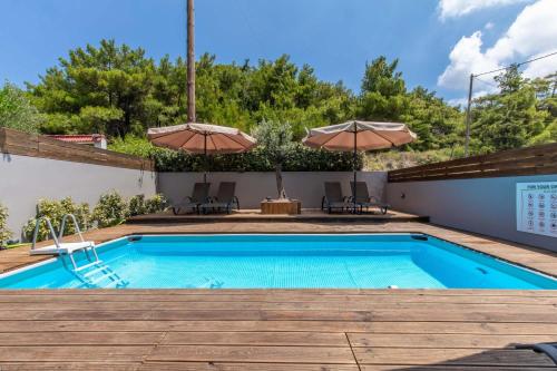 a swimming pool with two umbrellas on a patio at Akalli Luxury Studios in Ixia