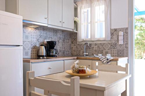 a kitchen with white cabinets and a table and chairs at Helen's Minimal Studios & Apartments in Aliki