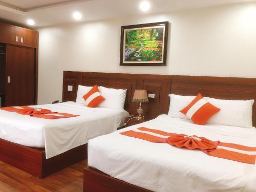 two beds in a hotel room with white and orange pillows at Gia Quý Hotel in Cao Bằng