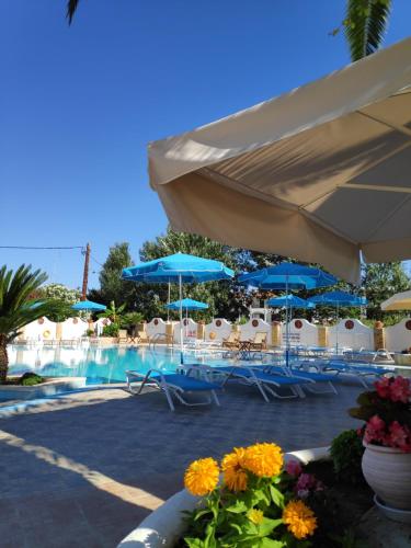 a swimming pool with blue umbrellas and tables and chairs at Estia hotel in Fourka