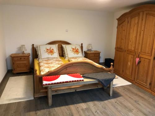 a bedroom with a wooden bed and two dressers at Ferienwohnung „Frosch“ in Neukirchen-Balbini