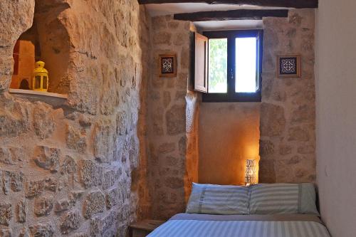 1 dormitorio con 1 cama en una pared de piedra en Casa Manolita, en Calaceite