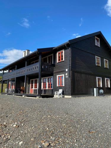 a large black building with red windows on a field at Hafjell Grenda lejligheder in Hafjell