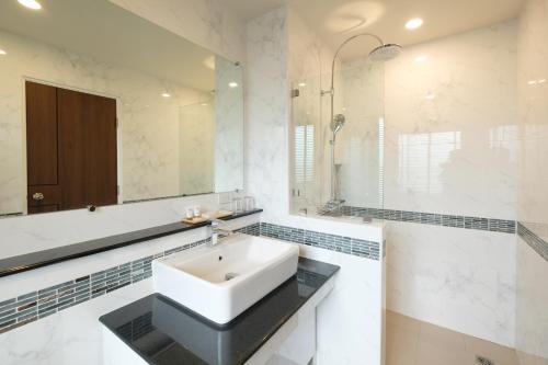 a white bathroom with a sink and a mirror at Monte Maesot hotel in Mae Sot